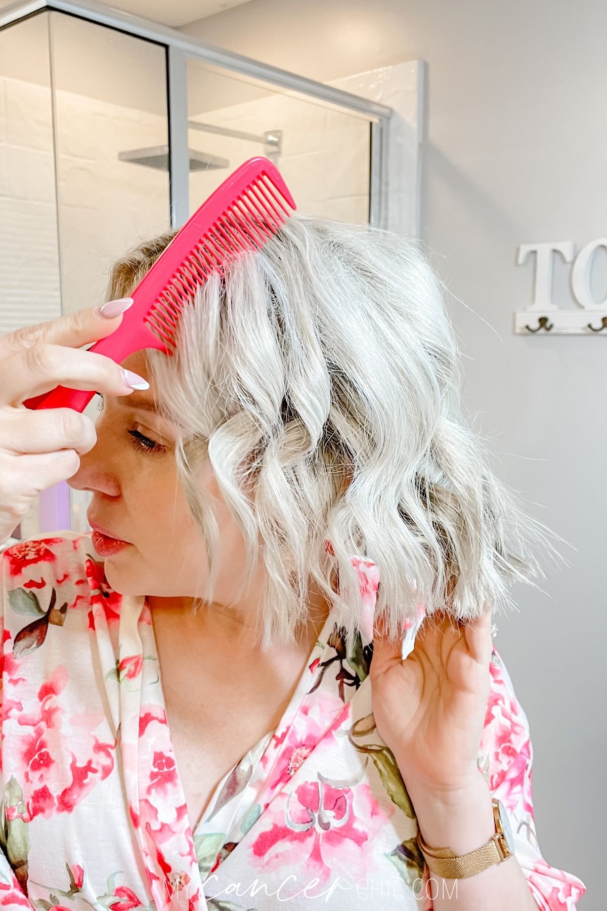 woman is combing her short hair after curling it