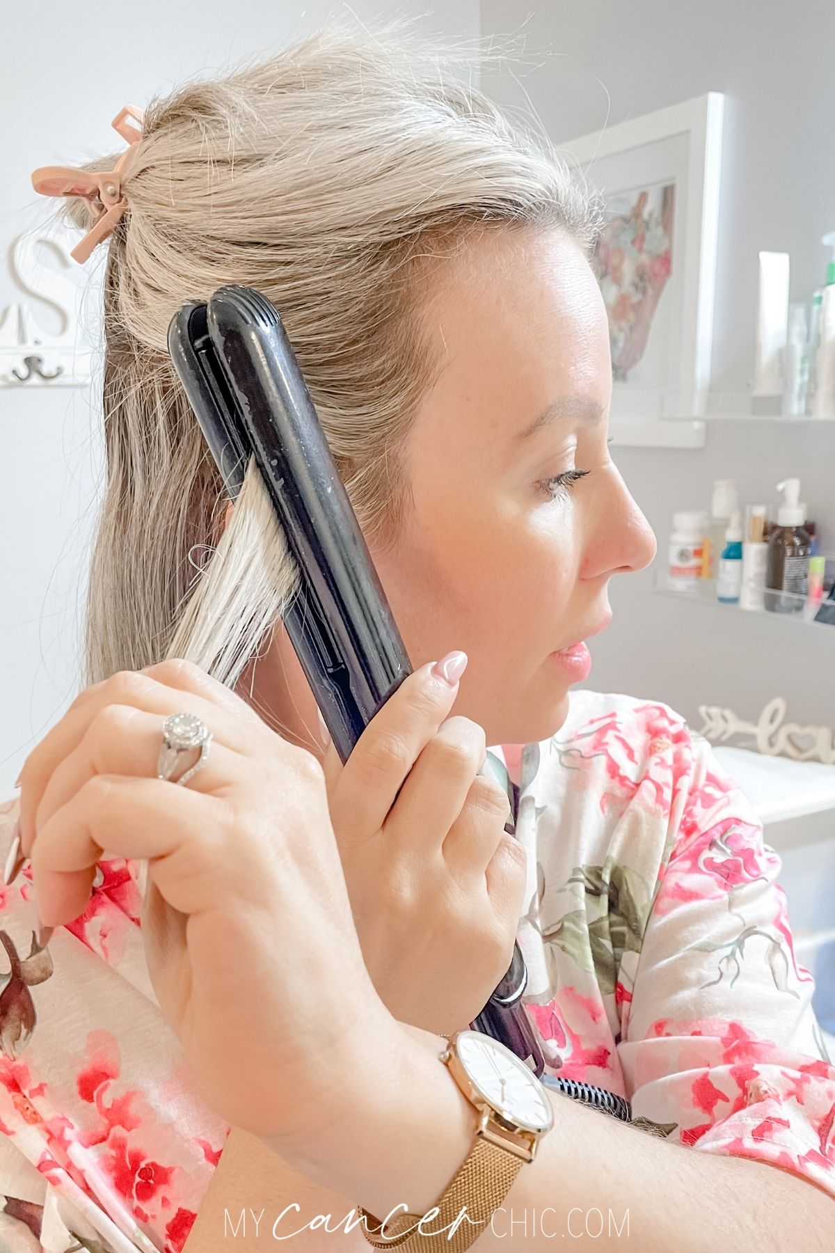 woman is using a flat iron to curl her short hair