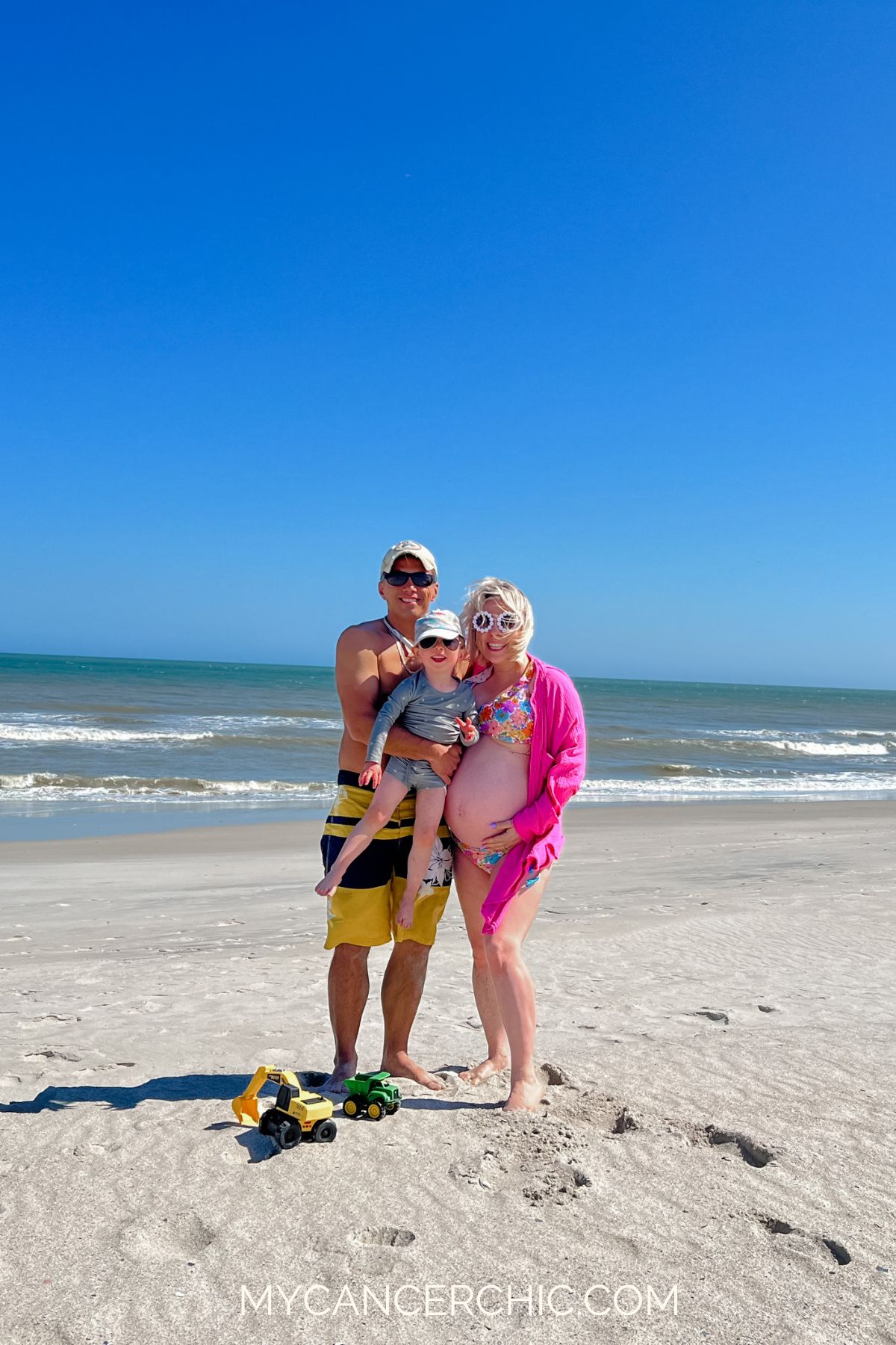 family of three on the beach while mother is pregnant with second child