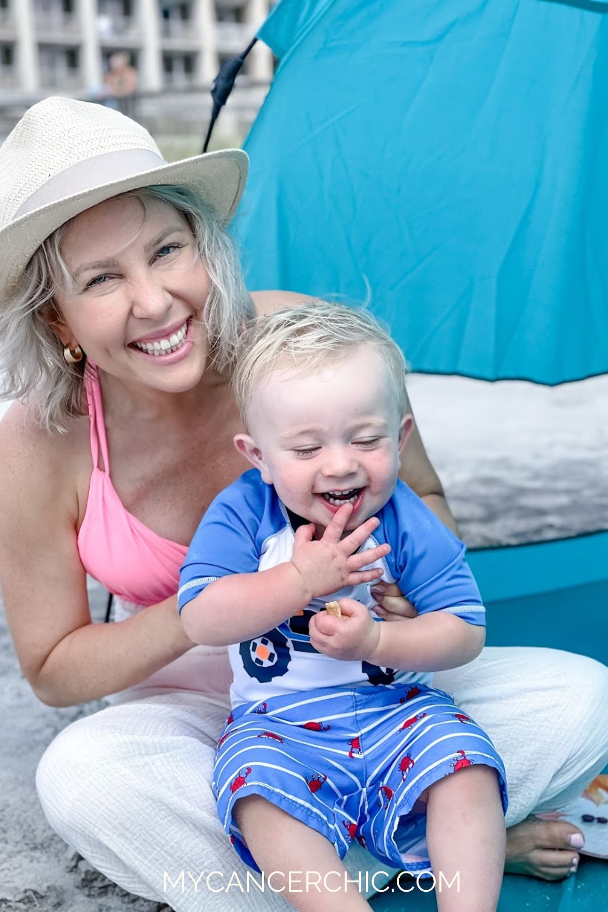 mom holding toddler son on the beach