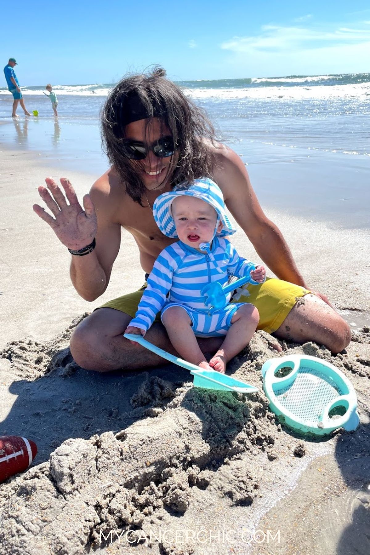 father playing with toddler son on the beach