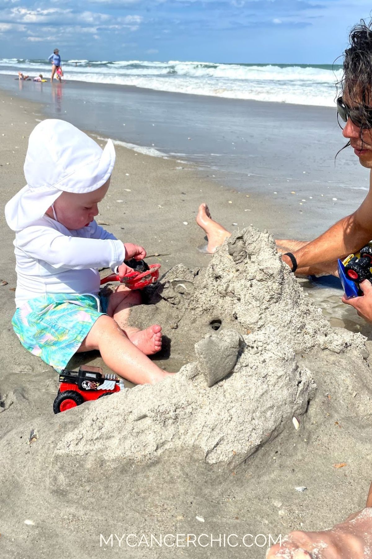 father playing with toddler son on the beach