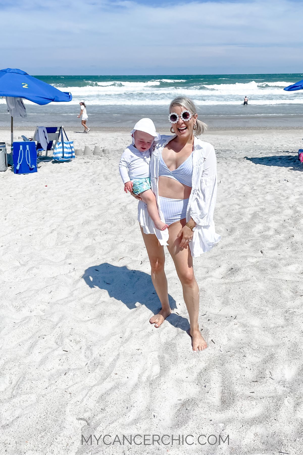 mother holding toddler son on the beach