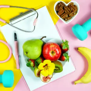 healthy living lifestyle changes after cancer fruits and dumbell and stethascope on pink and yellow background