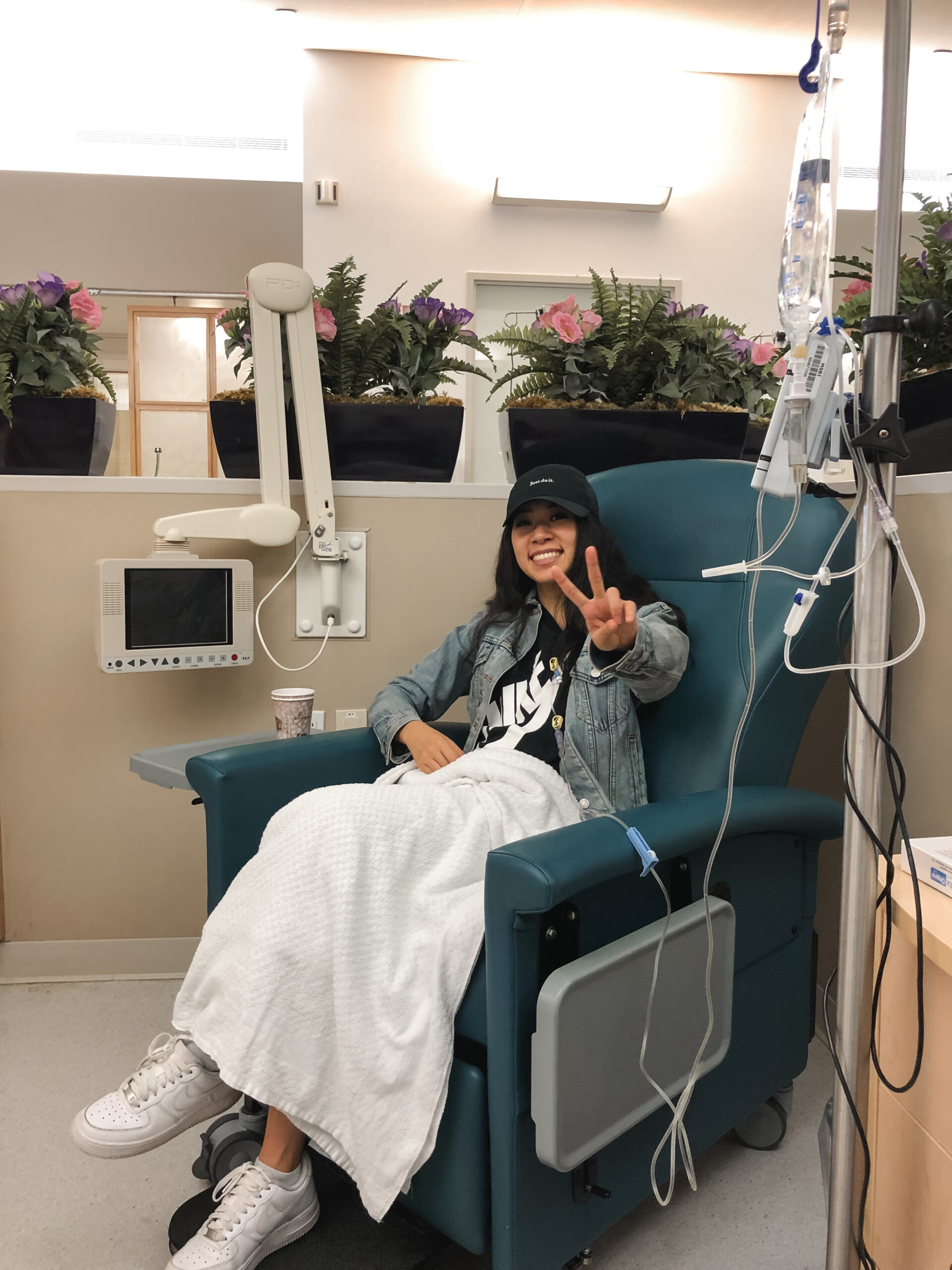woman in chemotherapy chair making peace sign