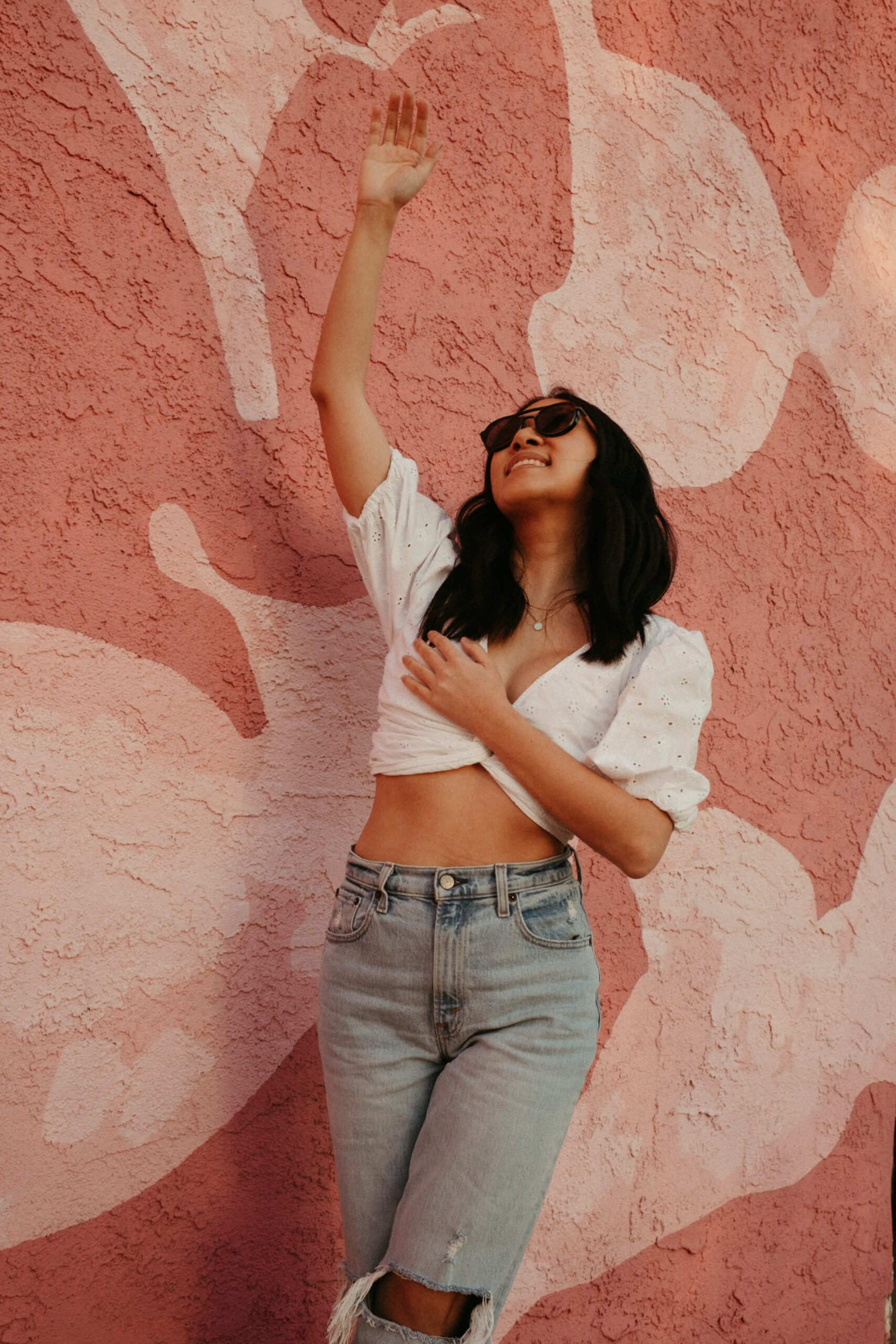 breast cancer survivor in front of pink stucco wall
