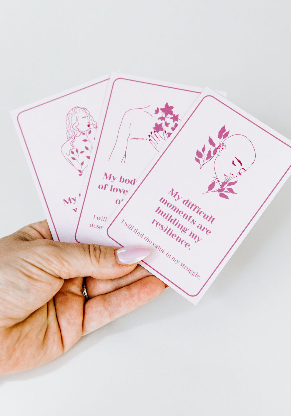 holding 3 affirmation cards with breast cancer scars